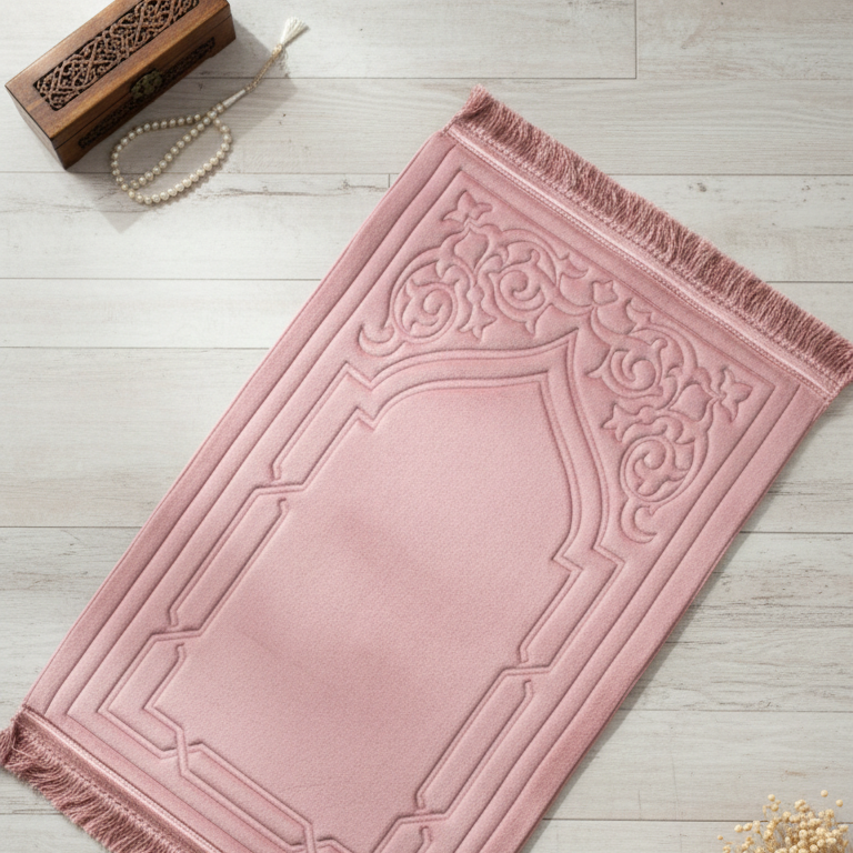 Pink prayer mat with decorative patterns on a light wooden floor.